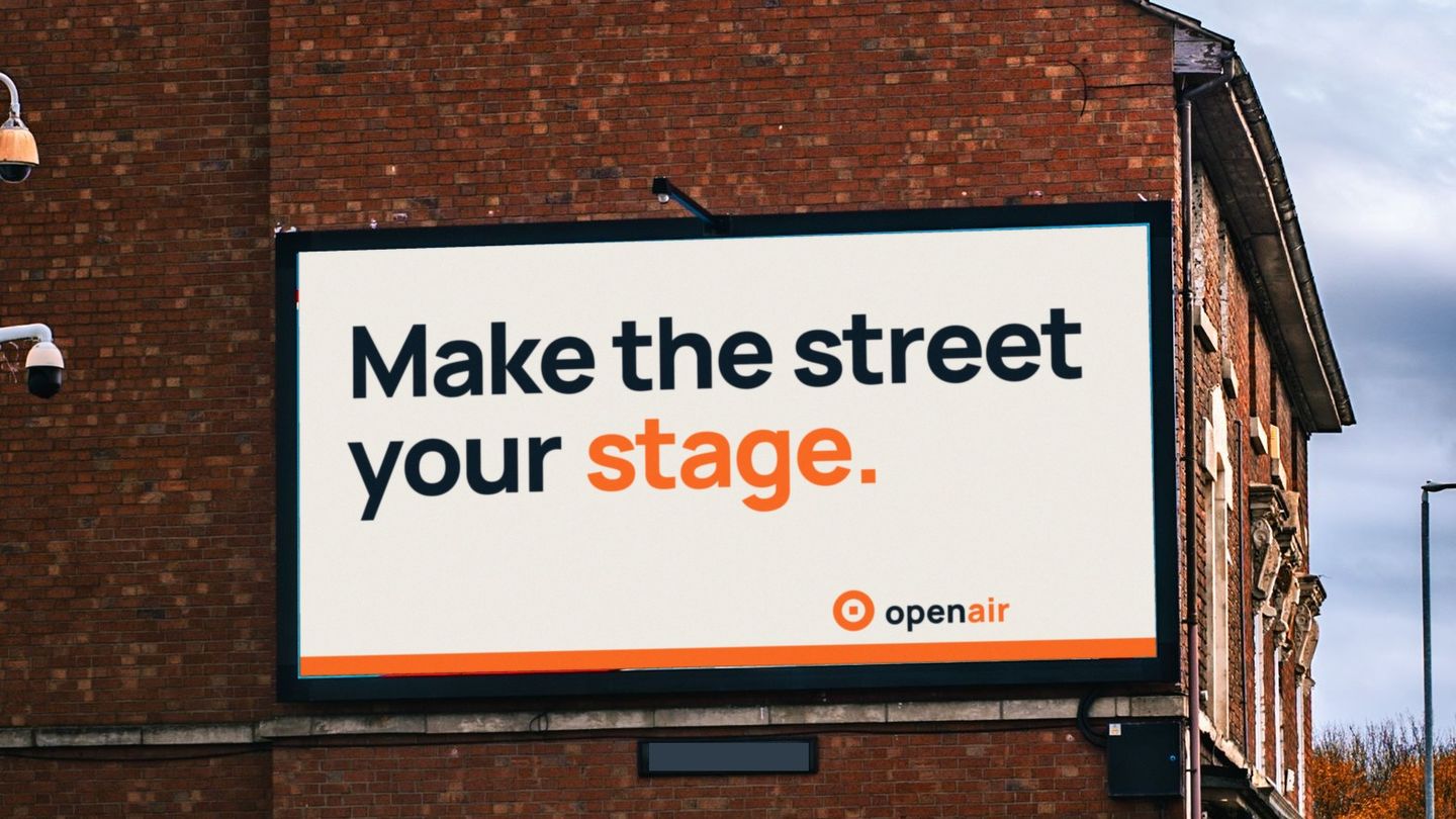 The same billboard showing an Open Air Media House poster that reads "Make the street your stage."