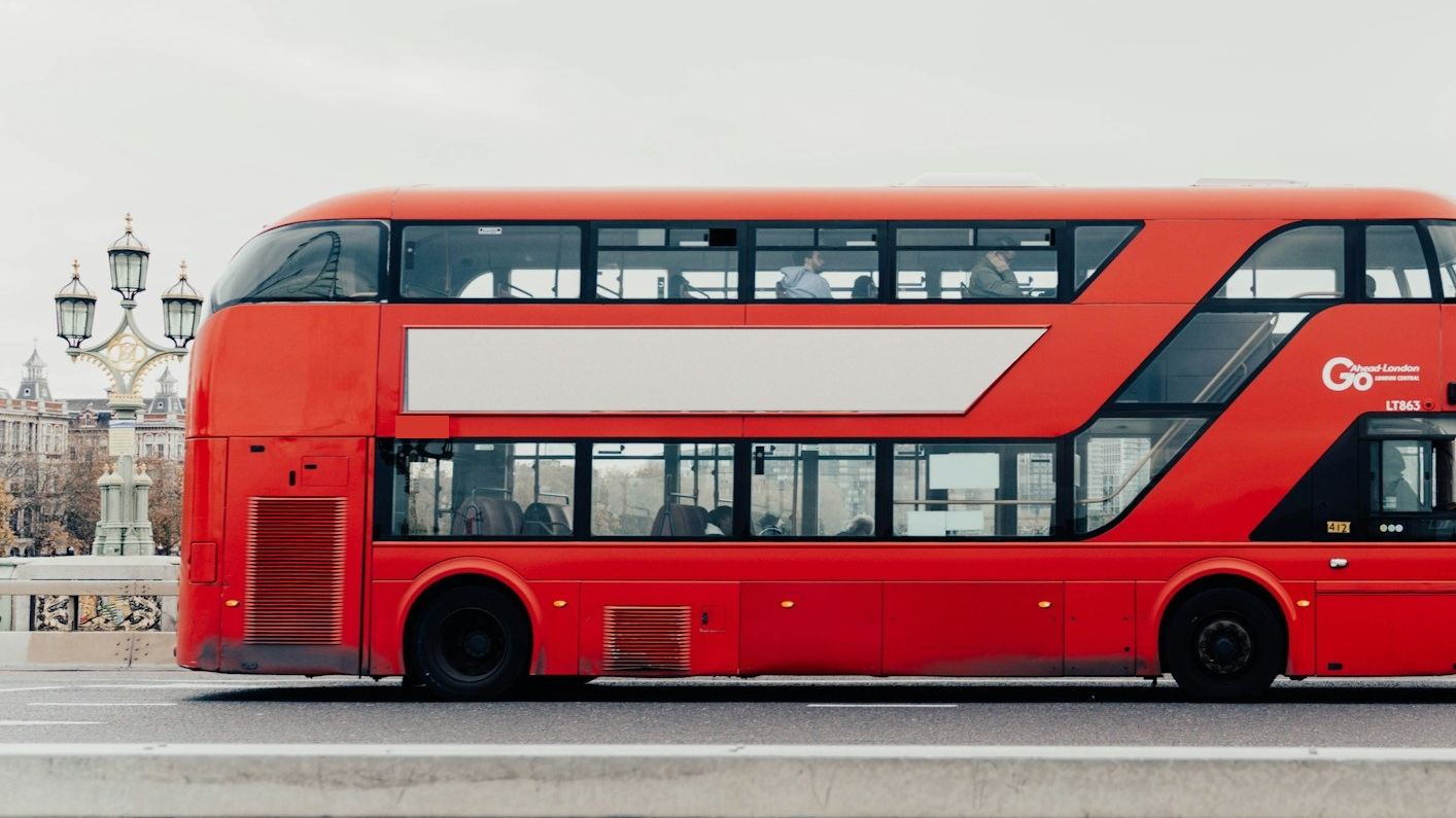 A red double-decker on Westminster Bridge with a blank side panel