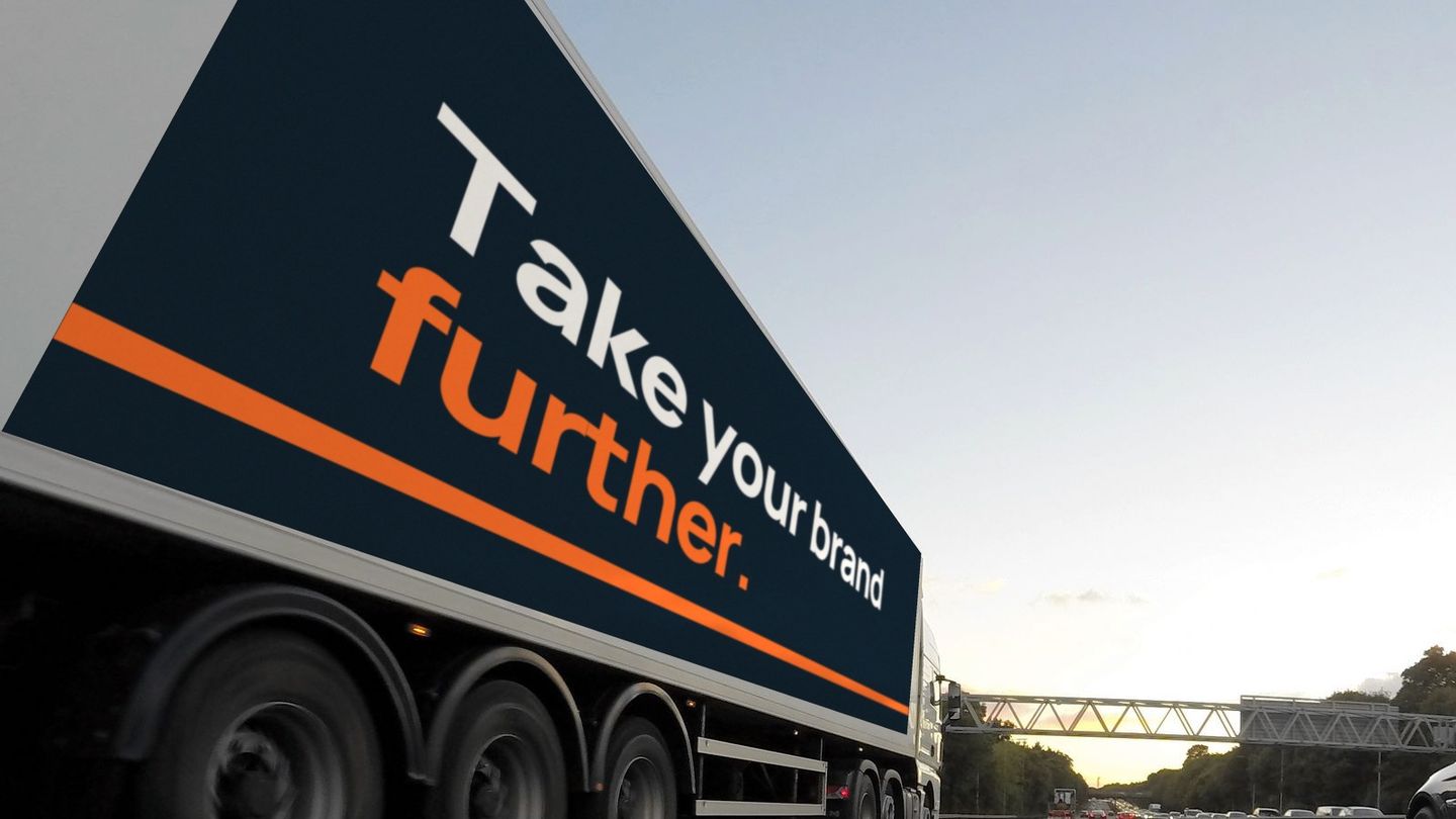 The same trailer wrapped in navy with the line "Take your brand further."